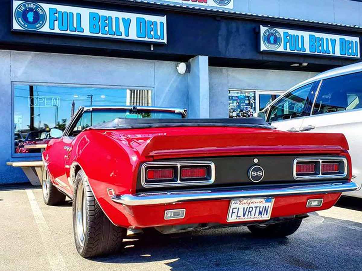 Guy Fieri’s signature red convertible parked in front of Full Belly Deli.